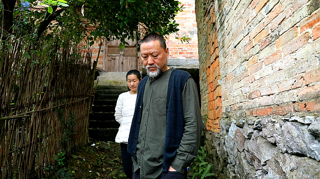 雕塑家刘松田在自己“收养”的老房子边上思考-a